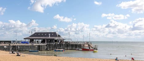 A beach with a pier, a lifeguard tower, and a sandy shore.