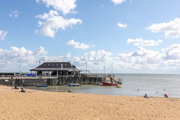 A beach with a pier, a lifeguard tower, and a sandy shore.