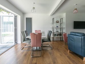 En moderne stue med spiseplads, en blå sofa og et fjernsyn ophængt på væggen.