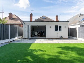 Une maison moderne avec un garage, une pelouse bien entretenue et un ciel dégagé.