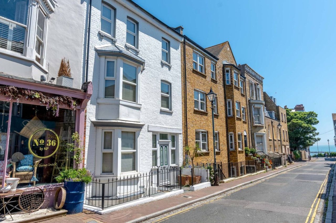 A row of traditional British terraced houses with a shop on the ground floor.