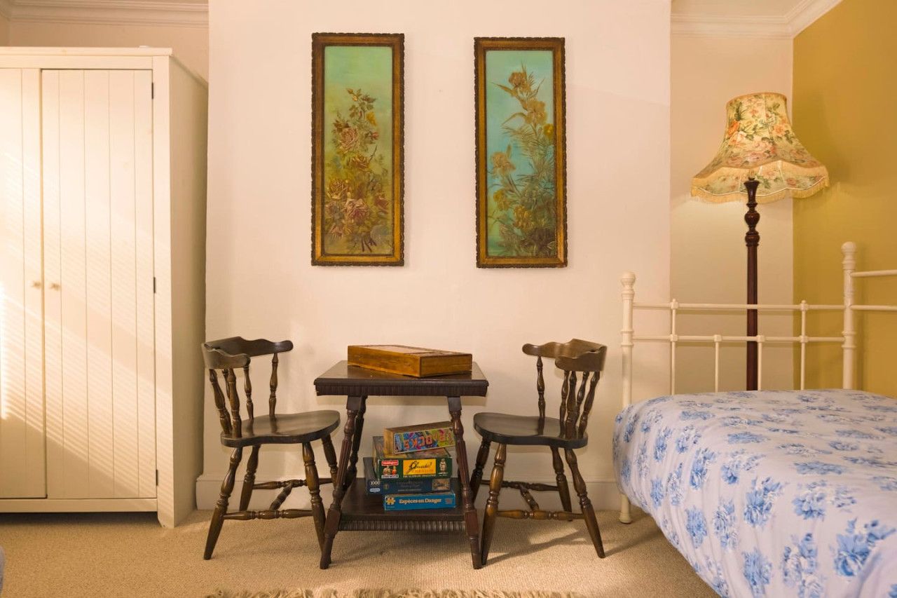 A bedroom with a bed, a nightstand, a lamp, and a dresser.