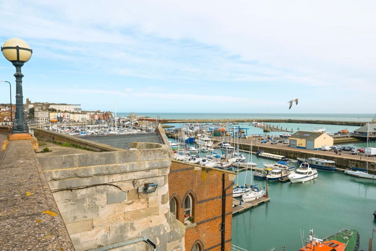 A harbor with boats, a lighthouse, and buildings in the background.