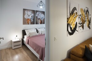 A bedroom with a bed, bedside table, and artwork on the wall.