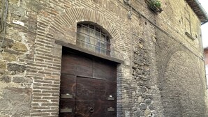 A historic building with a large wooden double door, a small arched window, and a brick facade. - Le Balze Bright penthouse with secluded panoramic terrace 200 mt from the Duomo (Perugia)