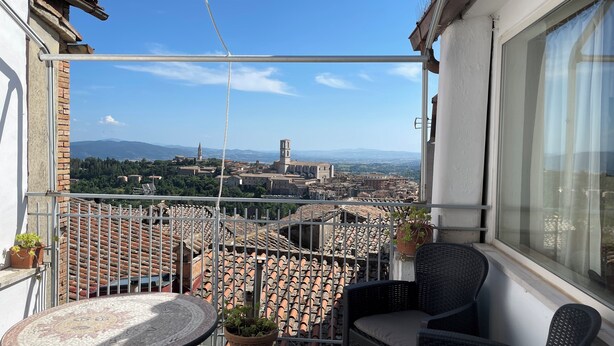 A balcony with a view of a cityscape, a round table, and two wicker chairs. - Le Balze Bright penthouse with secluded panoramic terrace 200 mt from the Duomo (Perugia)