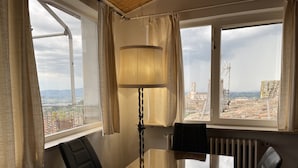A room with a large window, a table, a chair, and a lamp. - Le Balze Bright penthouse with secluded panoramic terrace 200 mt from the Duomo (Perugia)