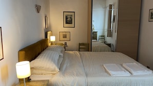 A hotel room with a bed, a nightstand with a lamp, a wooden headboard, a mirror, and a dresser. - Le Balze Bright penthouse with secluded panoramic terrace 200 mt from the Duomo (Perugia)