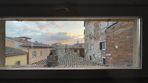 A view through a window of a narrow street with buildings on either side, leading to a small plaza. - Le Balze Bright penthouse with secluded panoramic terrace 200 mt from the Duomo (Perugia)