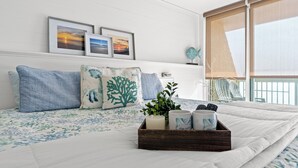 A bedroom with a bed, pillows, a tray with a candle, and framed pictures on the wall.