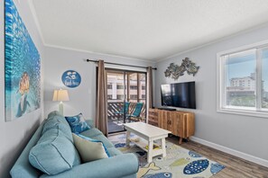 Relax in this stylish living room with a sofa, coffee table, and flat-screen TV, offering a balcony with a view.