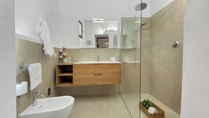 Un baño moderno con ducha de vidrio, tocador de madera y lavamanos blanco.