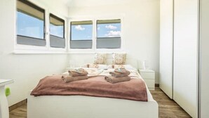 Un dormitorio con cama, dos mesitas de noche y una ventana con vistas al cielo.