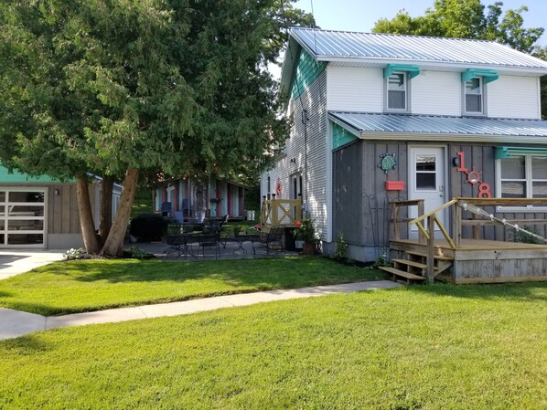 A house with a garage, a small deck, and a large tree in the yard. - Spacious yet cozy, newly remodeled home steps away from the Surf Ballroom. (Clear Lake)