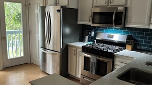 A modern kitchen with white cabinets, stainless steel appliances, and a blue tiled backsplash.