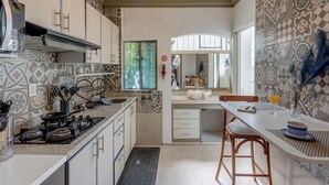 Cocina con estufa a gas, lavamanos y electrodomésticos modernos. Cuenta con un comedor con mesa y sillas, y una ventana con vistas al exterior.