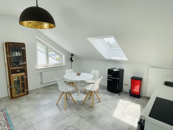 A modern kitchen with a skylight, white cabinets, and a black refrigerator. - A bright and spacious attic apartment. (Koblenz)