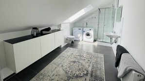 Un baño moderno con tragaluz, lavadora, inodoro y lavamanos.