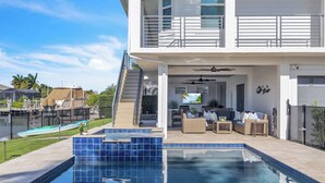 A two-story house with a swimming pool, outdoor seating, and a staircase leading to the upper level. - Gorgeous Waterfront Home; WALK to Beach and shops (Marco Island)