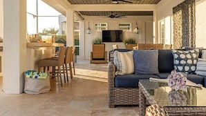 A spacious patio with a ceiling fan, wicker furniture, and a glass coffee table. - Gorgeous Waterfront Home; WALK to Beach and shops (Marco Island)