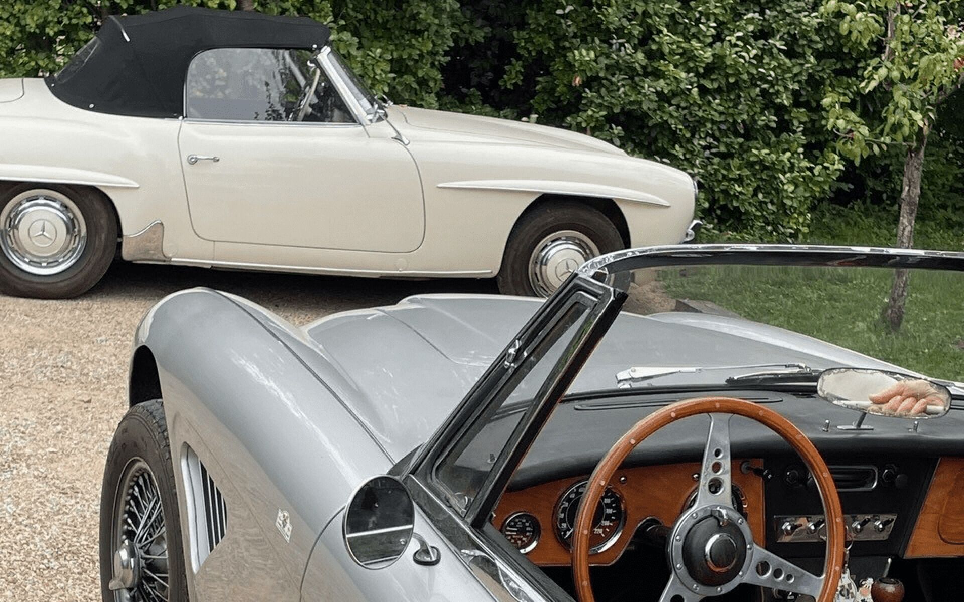 Een klassieke cabrio met een houten stuur en dashboard, geparkeerd buiten.