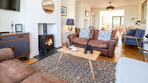 Una sala de estar acogedora con chimenea, sofá de cuero y televisor de pantalla plana.
