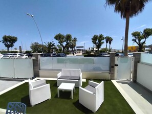 An outdoor seating area with white wicker furniture and a green artificial turf. - SAILING SUITE APARTMENT WITH A GARDEN ON THE BEACH (Alba Adriatica)