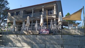 Un bâtiment doté d’une terrasse, une enseigne indiquant « Funcho D’Mina ASLADOR » et un mur de pierre au premier plan.