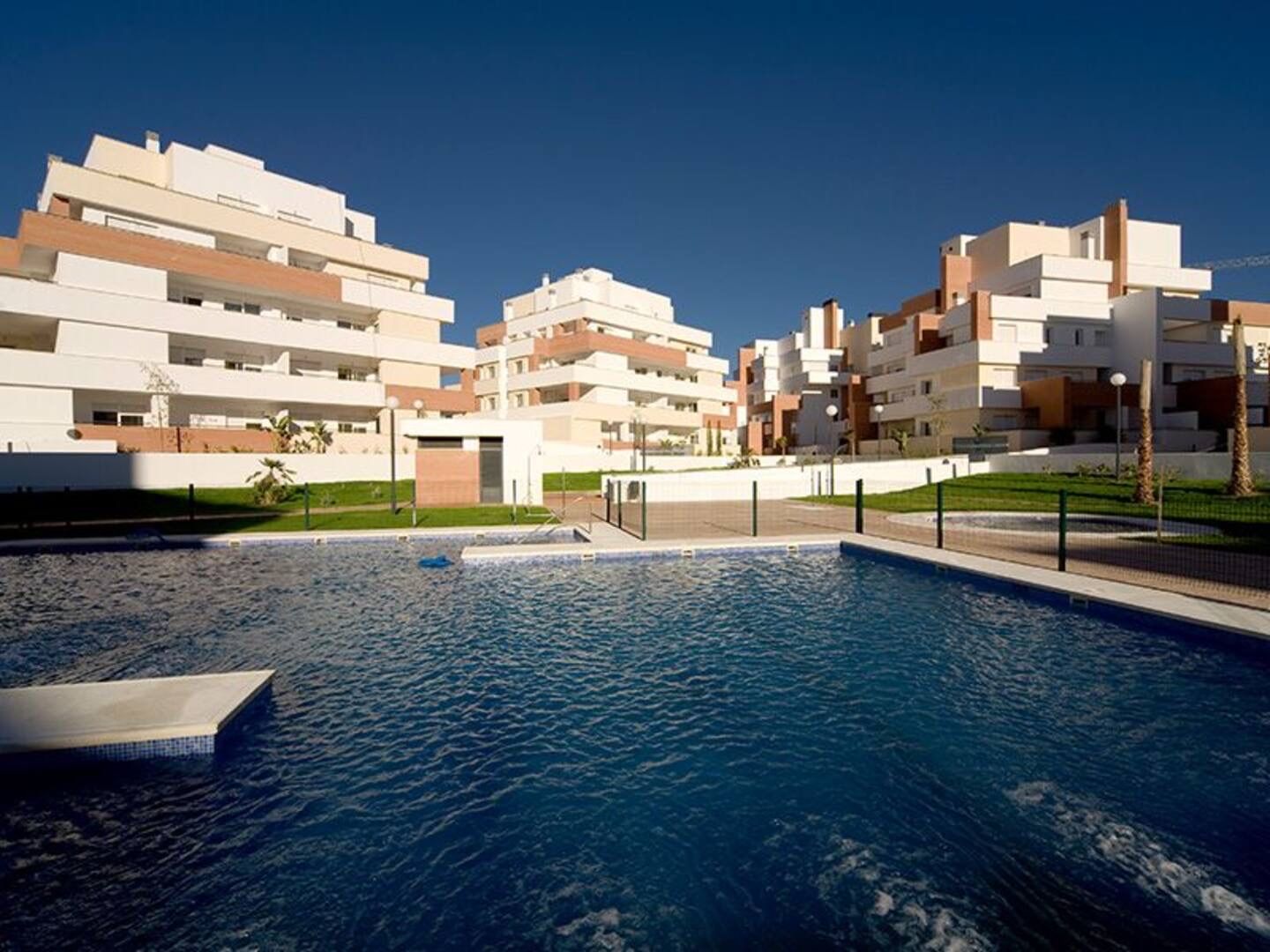 A modern residential building with a swimming pool in the foreground.