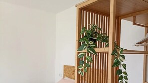Een minimalistische slaapkamer met een bed, een houten wandplank met planten, en keurig opgevouwen handdoeken.