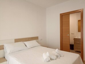A hotel room with a bed, a wooden wardrobe, and a bathroom visible through an open door. - Casal do Crego (O Grove)