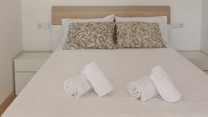 Ein ordentlich gemachtes Bett mit zwei Kissen und zwei zusammengerollten Handtüchern auf einer weißen Bettdecke.