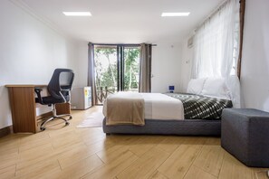 A bedroom with a bed, a desk, a chair, and a window with curtains.