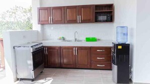 A kitchen with wooden cabinets, a stainless steel stove, a microwave, and a water dispenser. - The Treehouse Studio apartments with a large rooftop terrace. (Aburi-South)