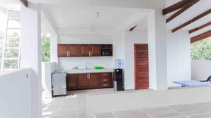 A kitchen with wooden cabinets, a sink, and a refrigerator. - The Treehouse Studio apartments with a large rooftop terrace. (Aburi-South)