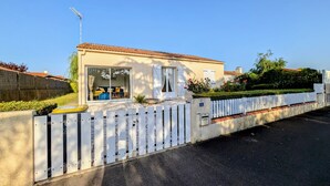 A single-story house with a tiled roof, a white picket fence, and a number 14 sign.