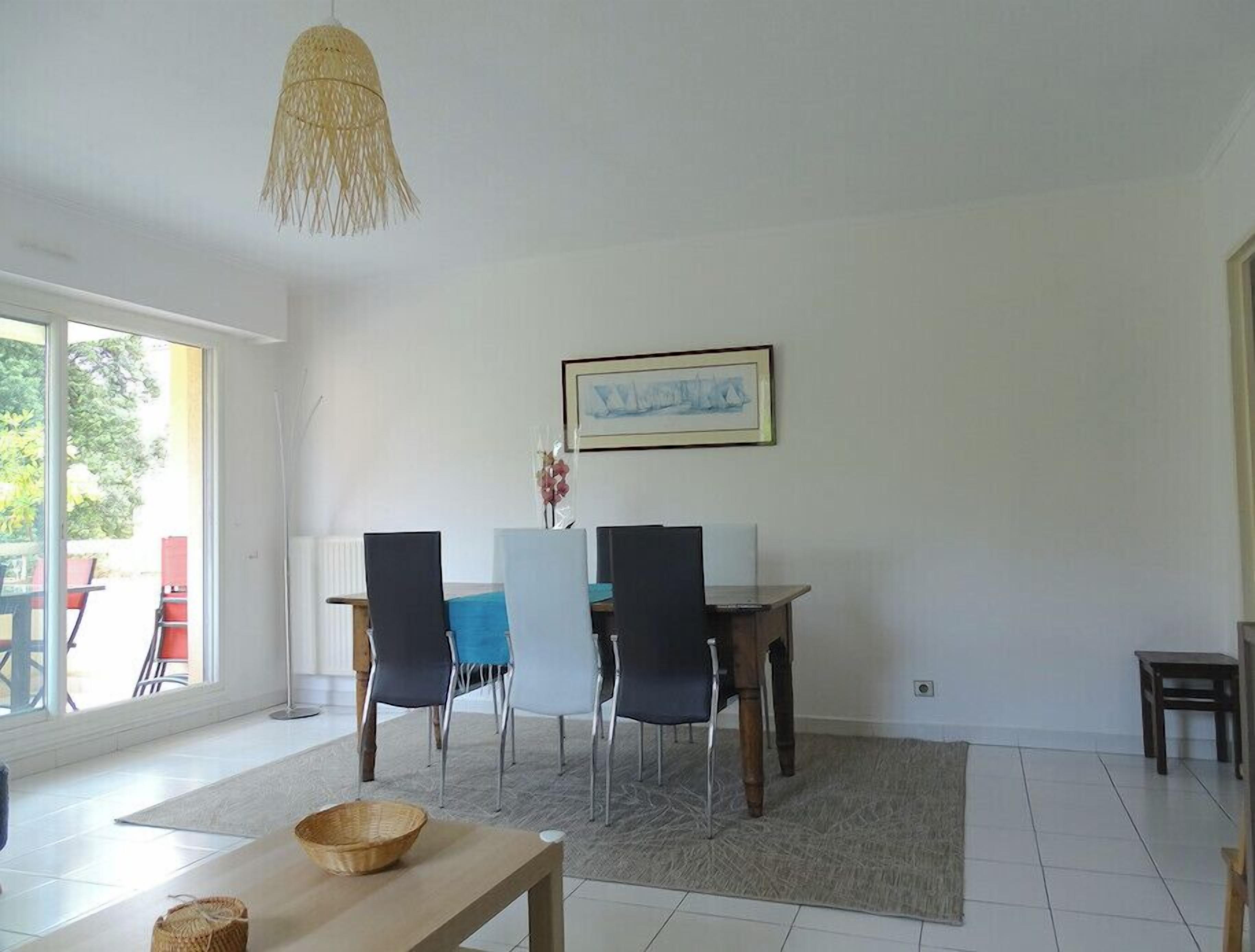 A dining area with a table, chairs, and a hanging light fixture.