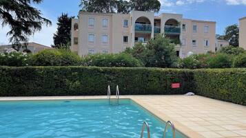 A rectangular swimming pool with two metal ladders, surrounded by a tiled deck.