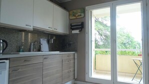 A kitchen with a sink, cabinets, and a window to a balcony. - Spacious cocoon with two terraces (Montpellier)