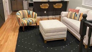 A living room with a sofa, striped armchair, ottoman, and a black rug with white dots. - Bayou on the Bay (Stevensville)