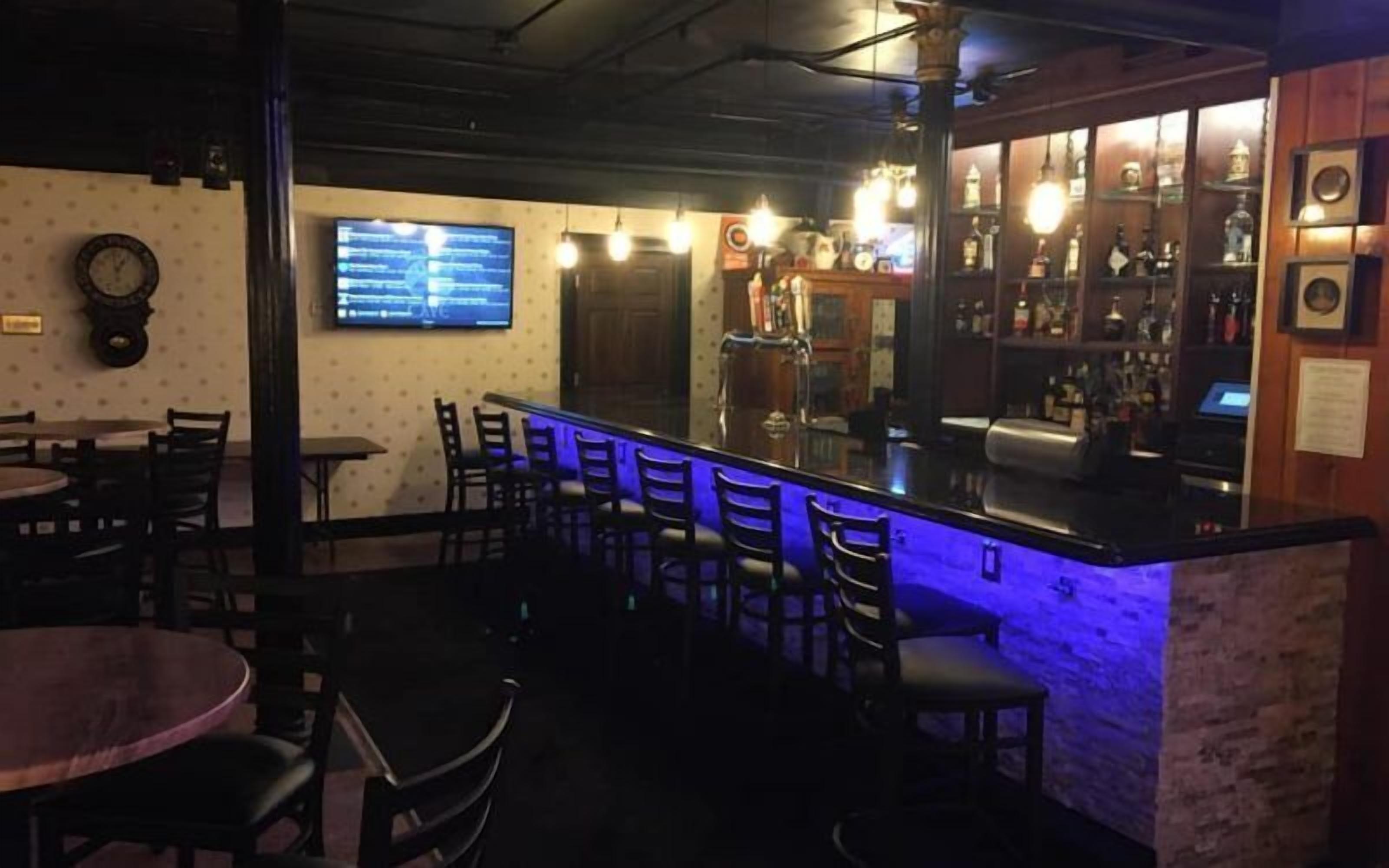 Zona de bar amb barra, seients i pantalla de televisió.