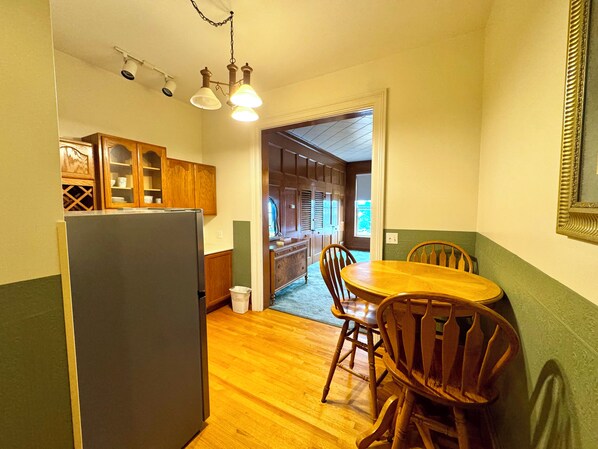 Une cuisine compacte équipée d’un réfrigérateur, de meubles de rangement en bois et d’un coin repas avec une table et des chaises.