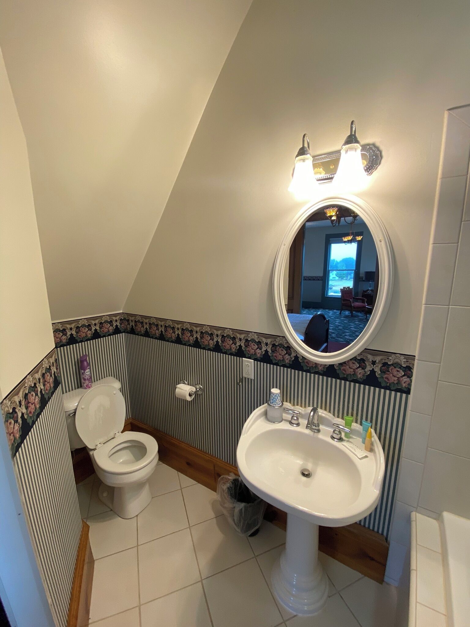 Een badkamer met toilet, wastafel en spiegel.