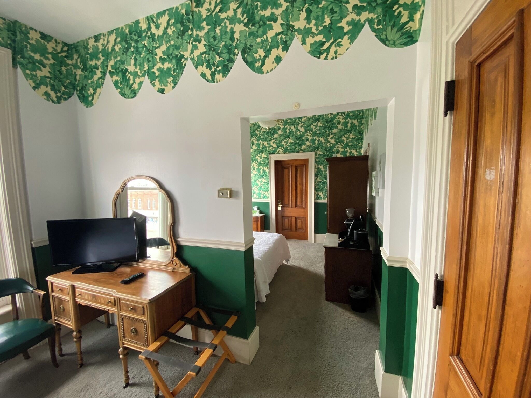 Une pièce comprenant un bureau en bois, une chaise, un lit, une armoire et une porte.
