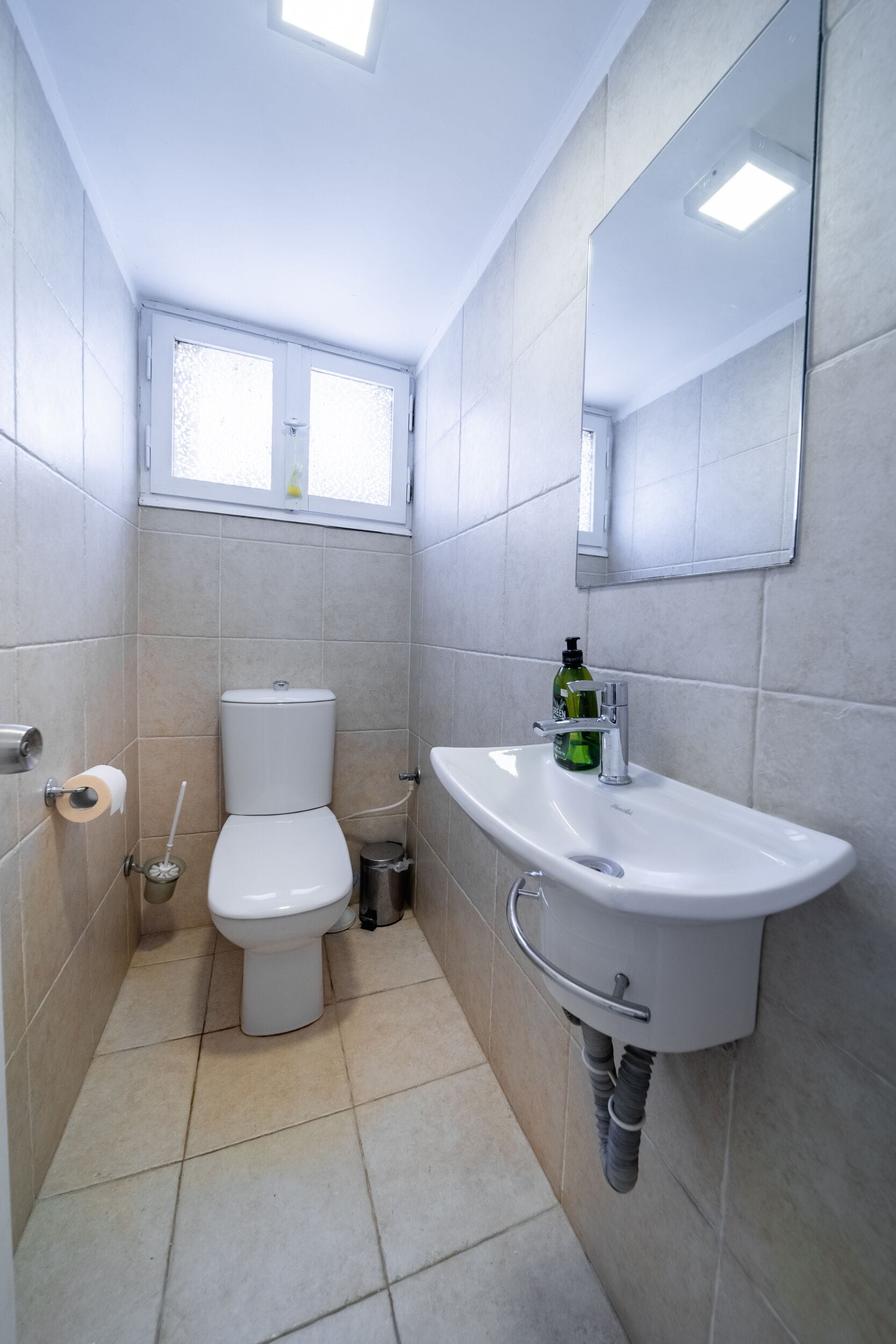 Un baño pequeño y moderno con inodoro, lavamanos y espejo.