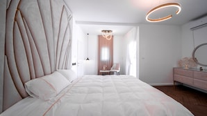 Quarto moderno com uma cama grande, uma mesa de toucador com espelho e um candelabro.