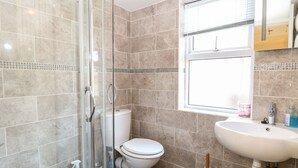 Une salle de bain avec une douche à parois de verre, des toilettes, un lavabo et une fenêtre.