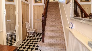 Un escalier avec un sol à carreaux, des portes en bois et une chaise.