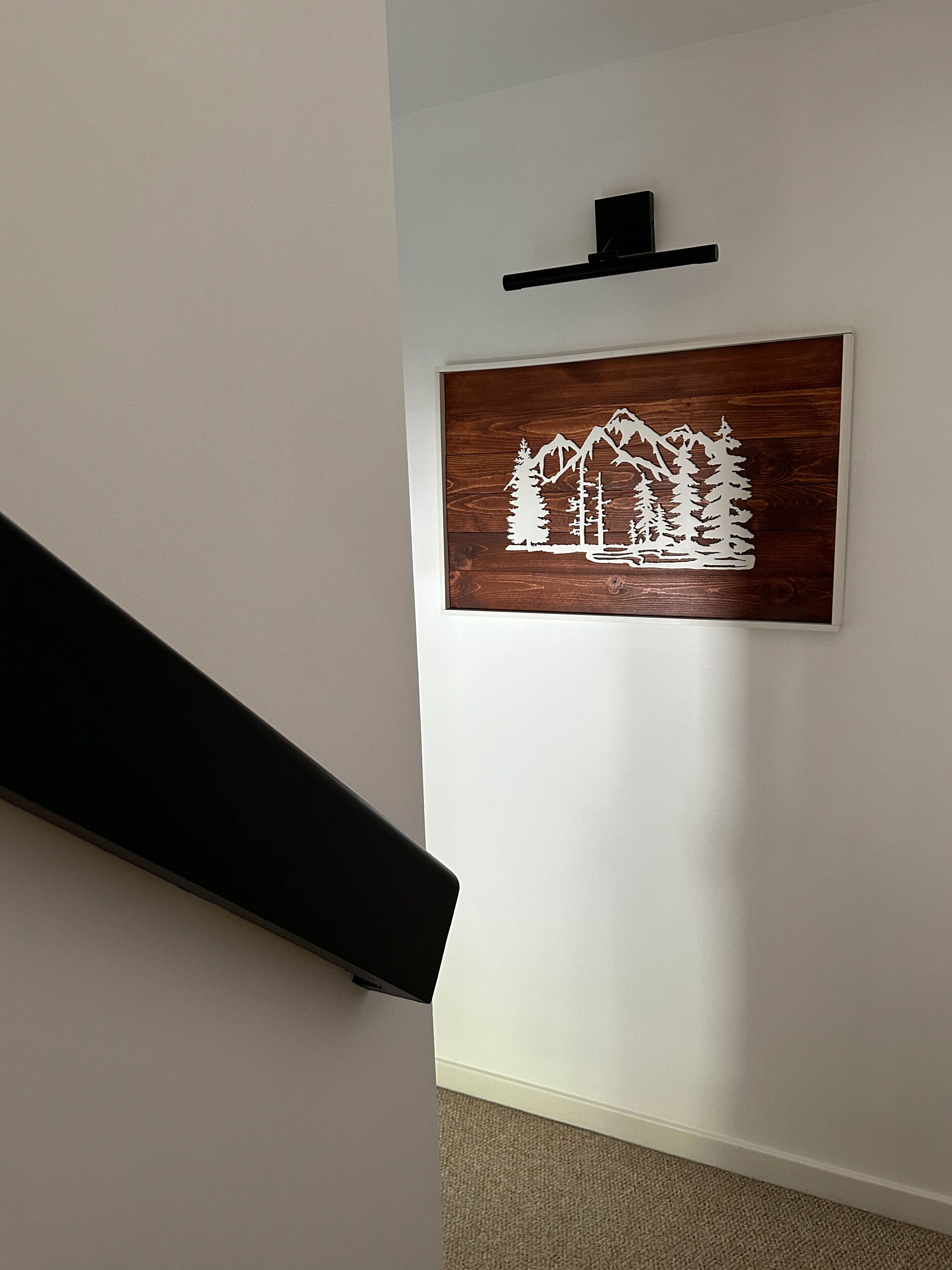 A staircase with a wooden wall art depicting a mountain scene.