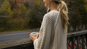 A person standing on a wooden bridge, holding a cup, with autumn trees and a road in the background. - Modern Mount Snow Gnarvana - Balcony, Loft, Pets, Hiking (Dover)